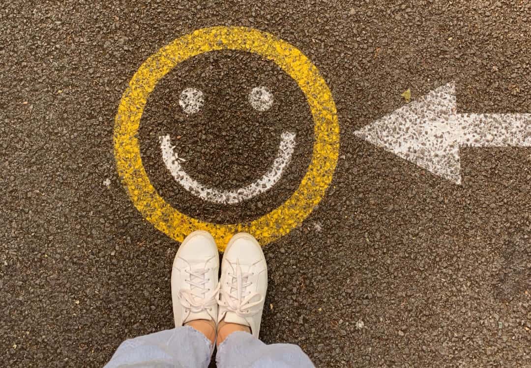 Eine Person steht auf einem Smiley, der auf den Boden gemalt wurde.