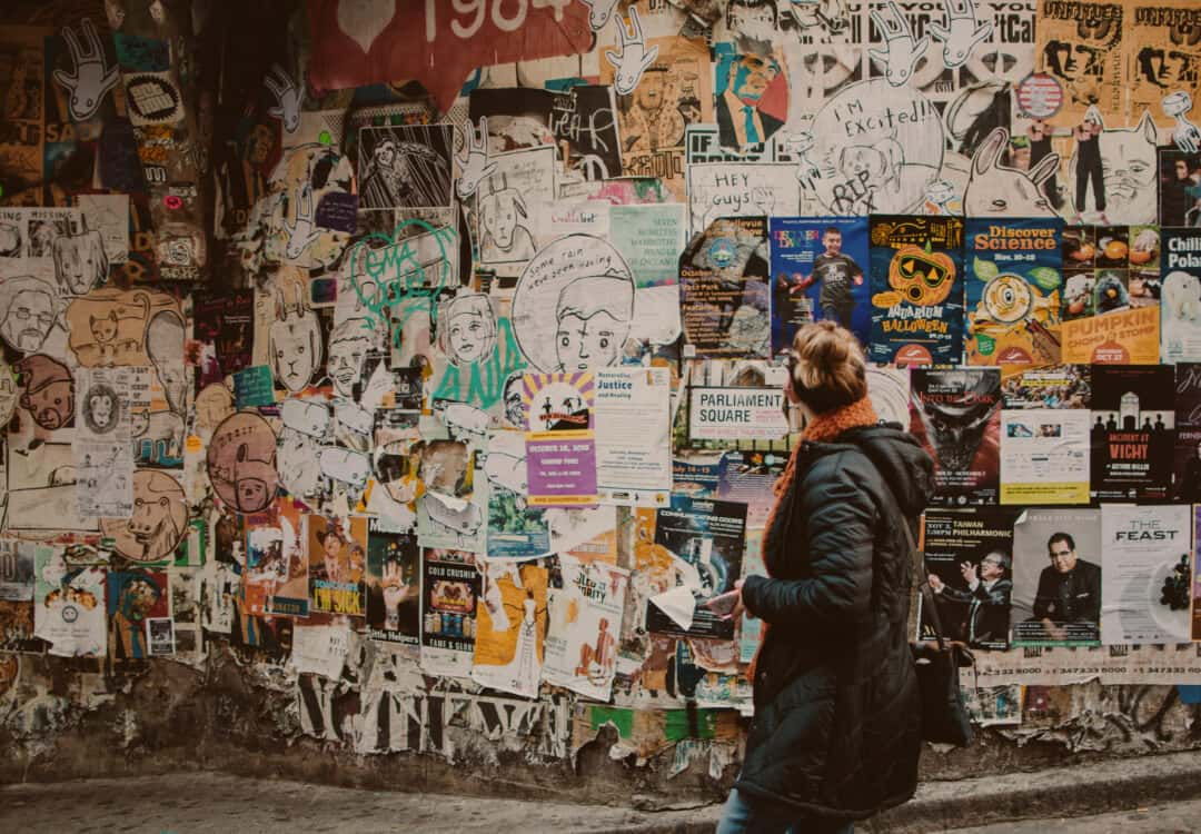 Eine Frau, die vor einer Wand voller Werbeanzeigen steht